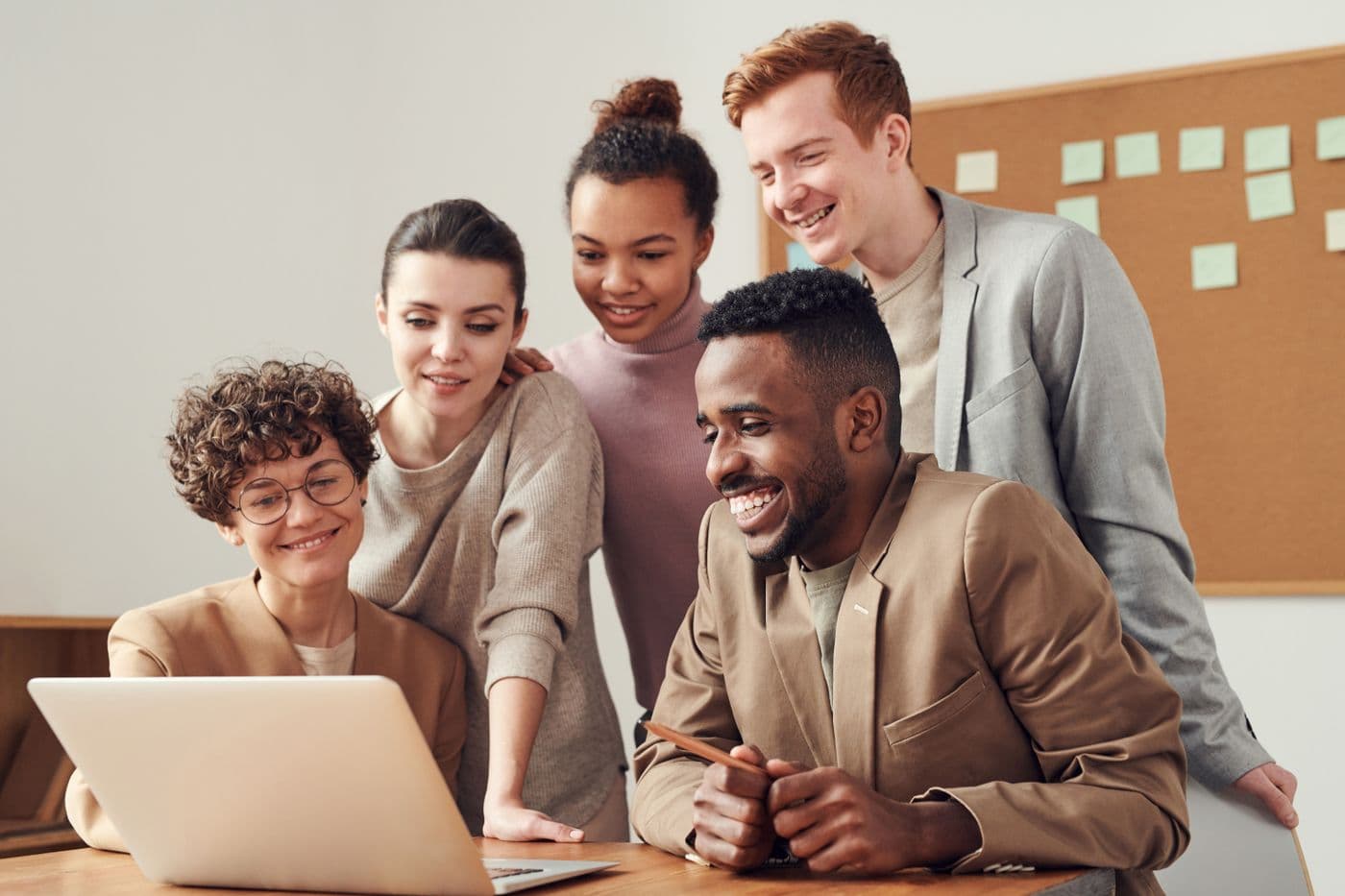 Small team collaborating around laptops in a meeting room