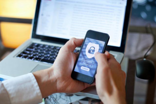 Secure login screen on a phone in front of a laptop