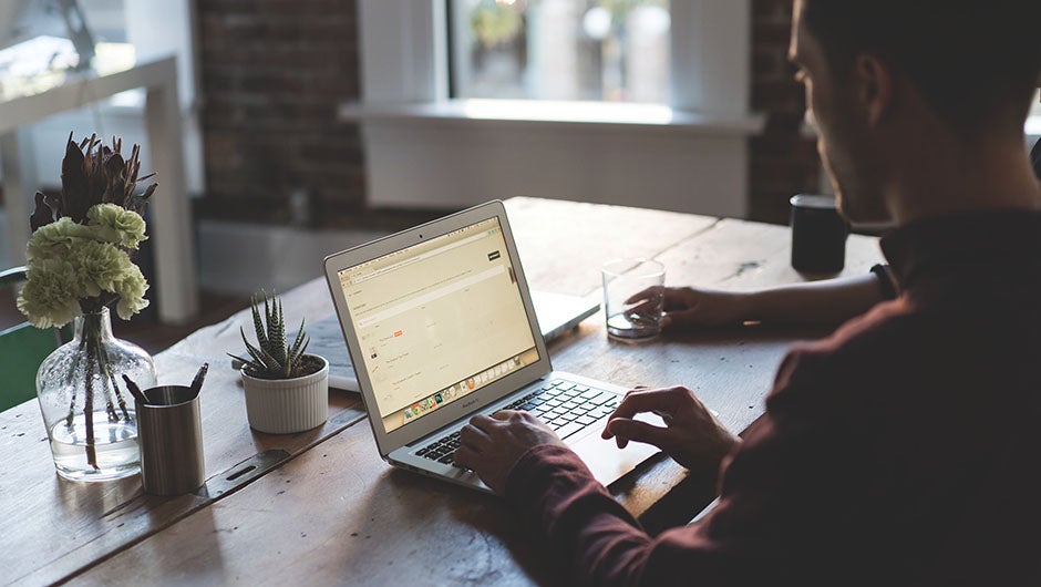 Person working on a laptop at a wooden table