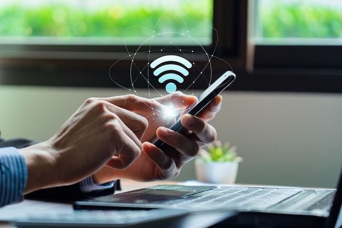 Person using a phone on Wi-Fi next to a laptop