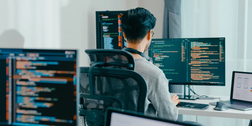 Developer working at a multi-screen desk in a small office
